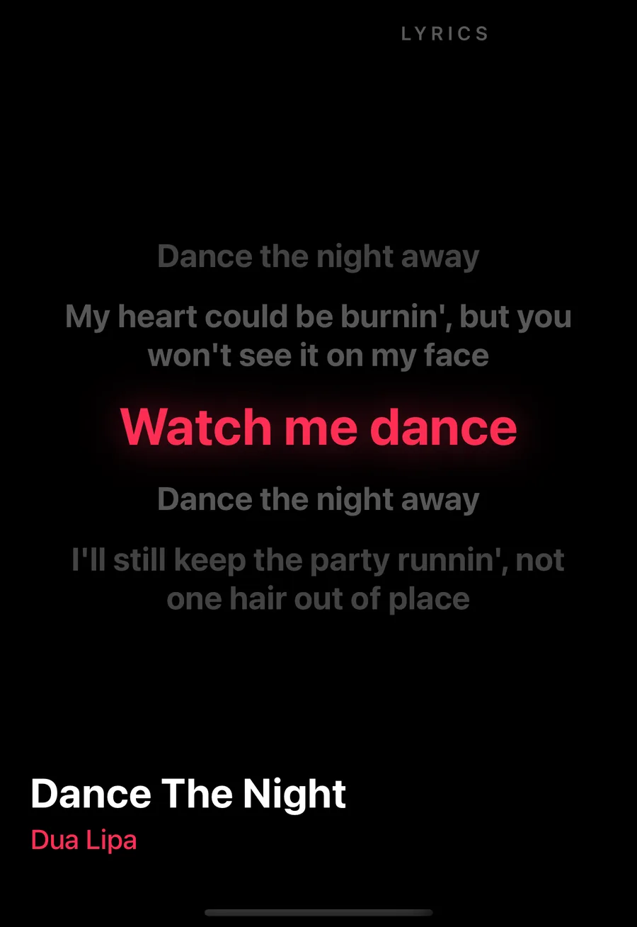 The phone's screensaver in its lyrics mode on the iPhone Duo's outer screen: Dance The Night by Dua Lipa, the line Watch me dance lit in red between dimmer lines above and below