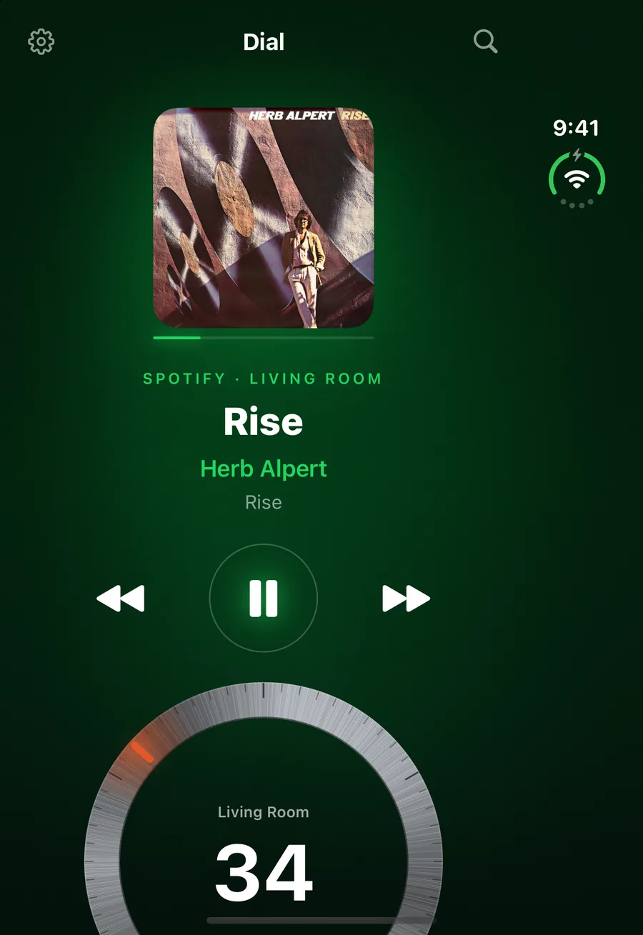 Dial on the iPhone Duo's outer screen: the Living Room playing Rise by Herb Alpert, transport under the record, and the dial at 34 on the first screen